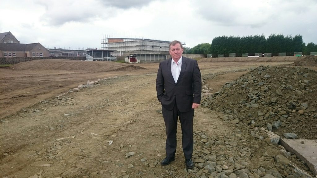 Alex Rowley viewing the ground works with the towering games hall in the background
